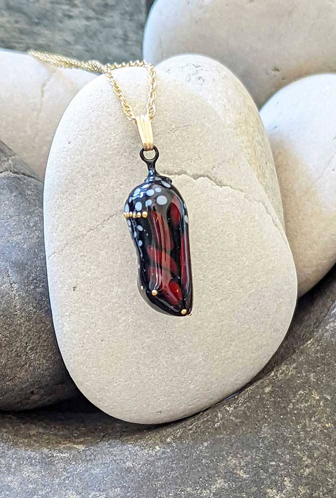 Almost-born glass chrysalis with 24k gold dots, the orange and black phase.