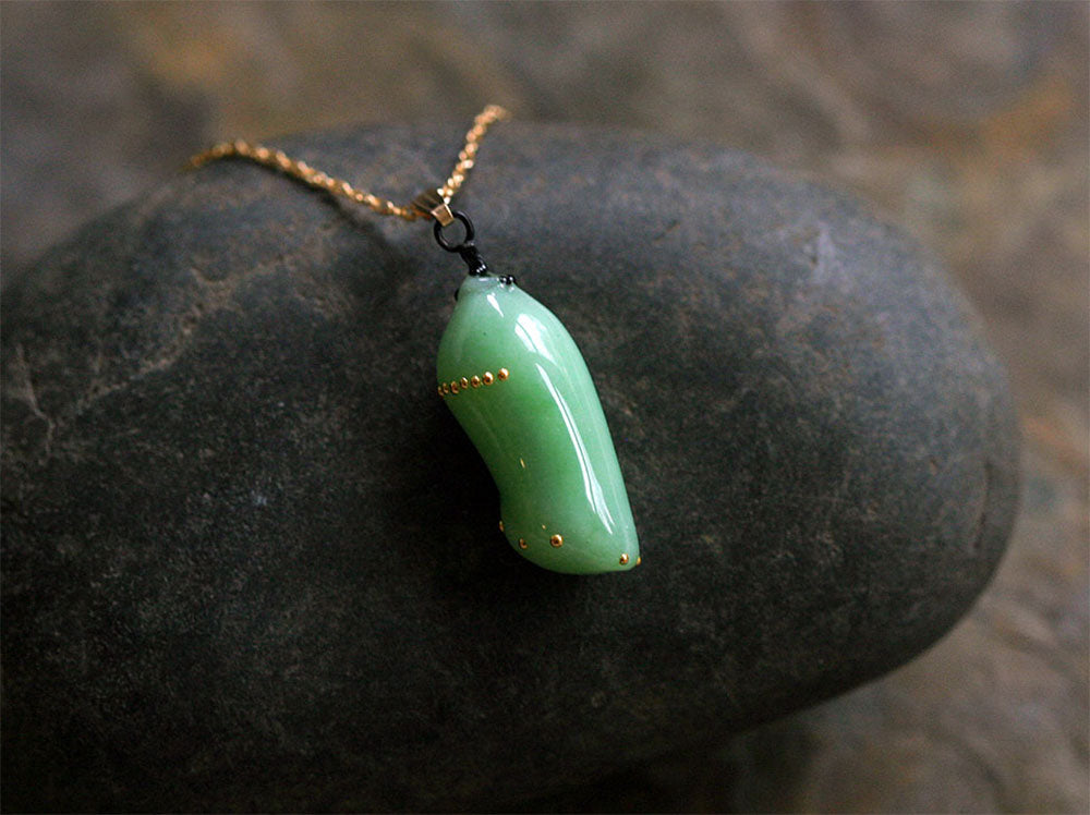 Monarch chrysalis replica on a stone made by glass artist Jude Rose